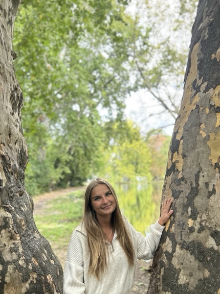 Pellei Kyra egy fa mellett áll